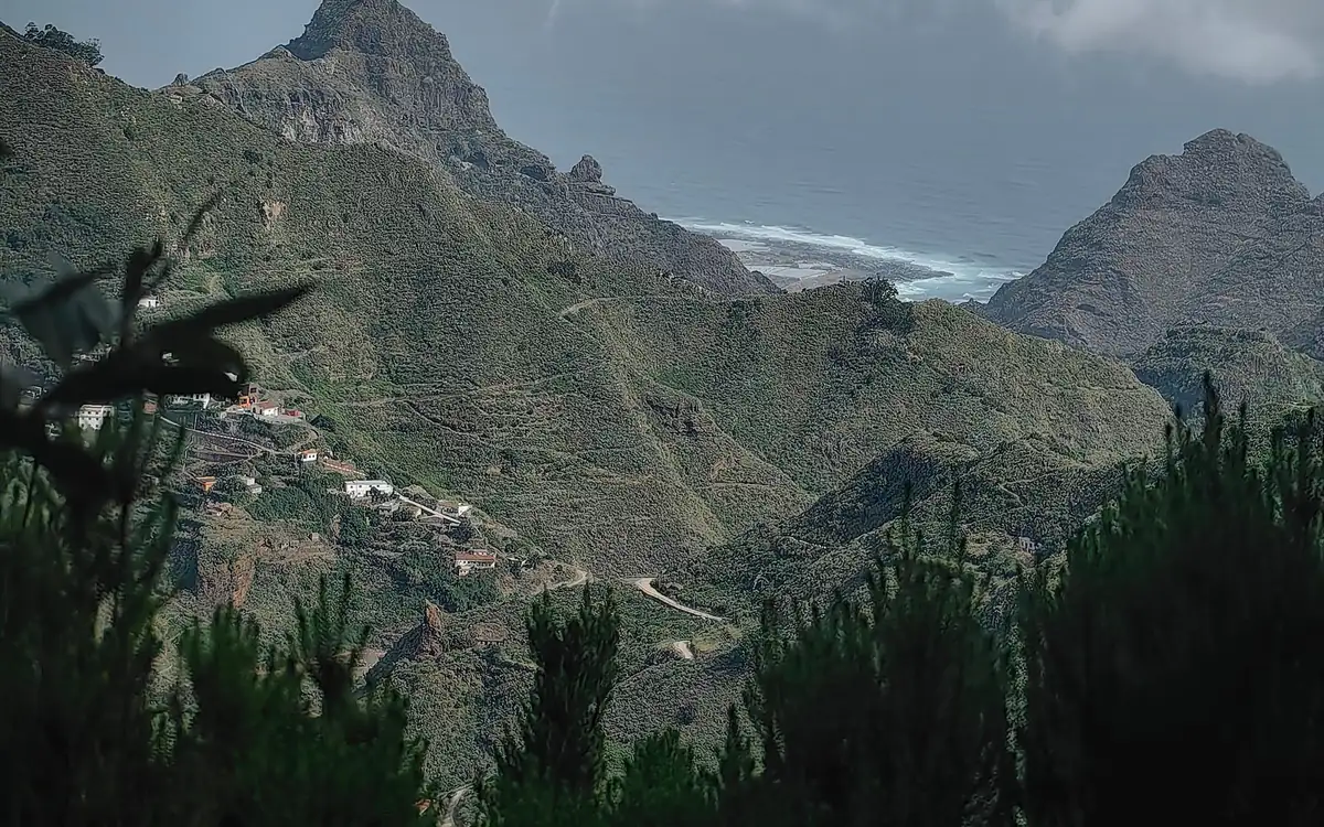 Crestas verdes y picos afilados sobre el Atlántico, con casas blancas en una ladera