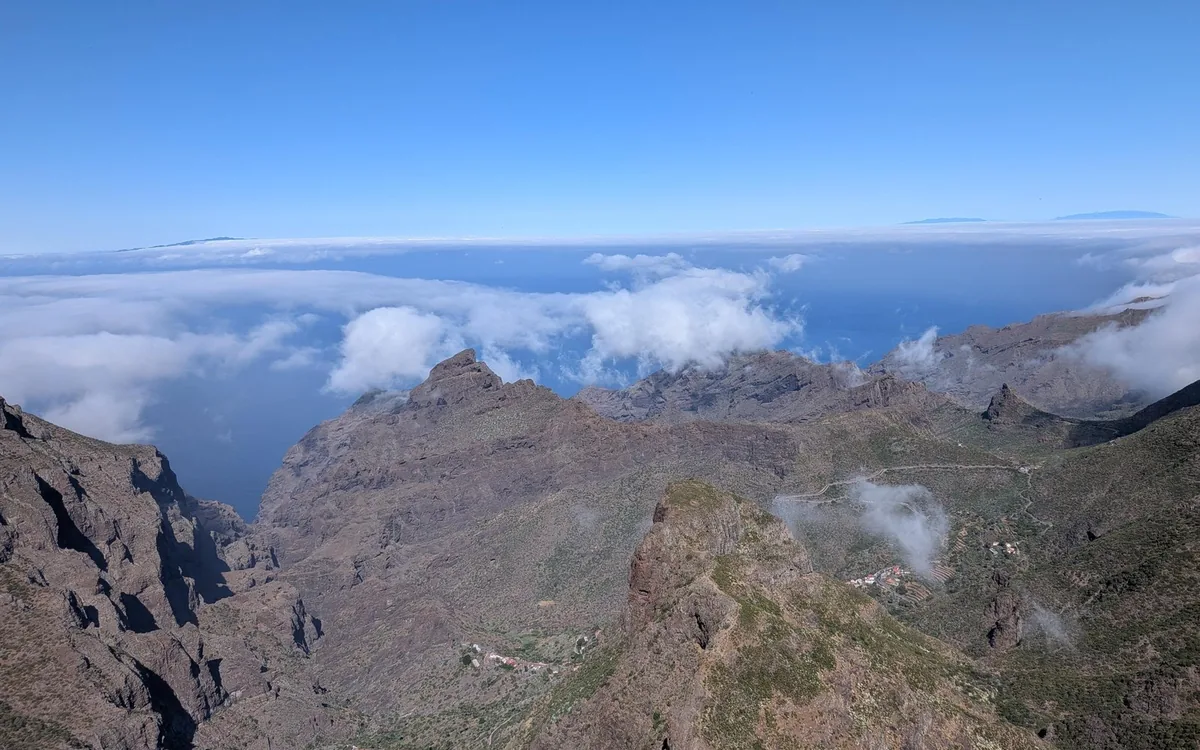 Jagged ridges and deep ravines seen from high ground, with white cloud lying between the peaks