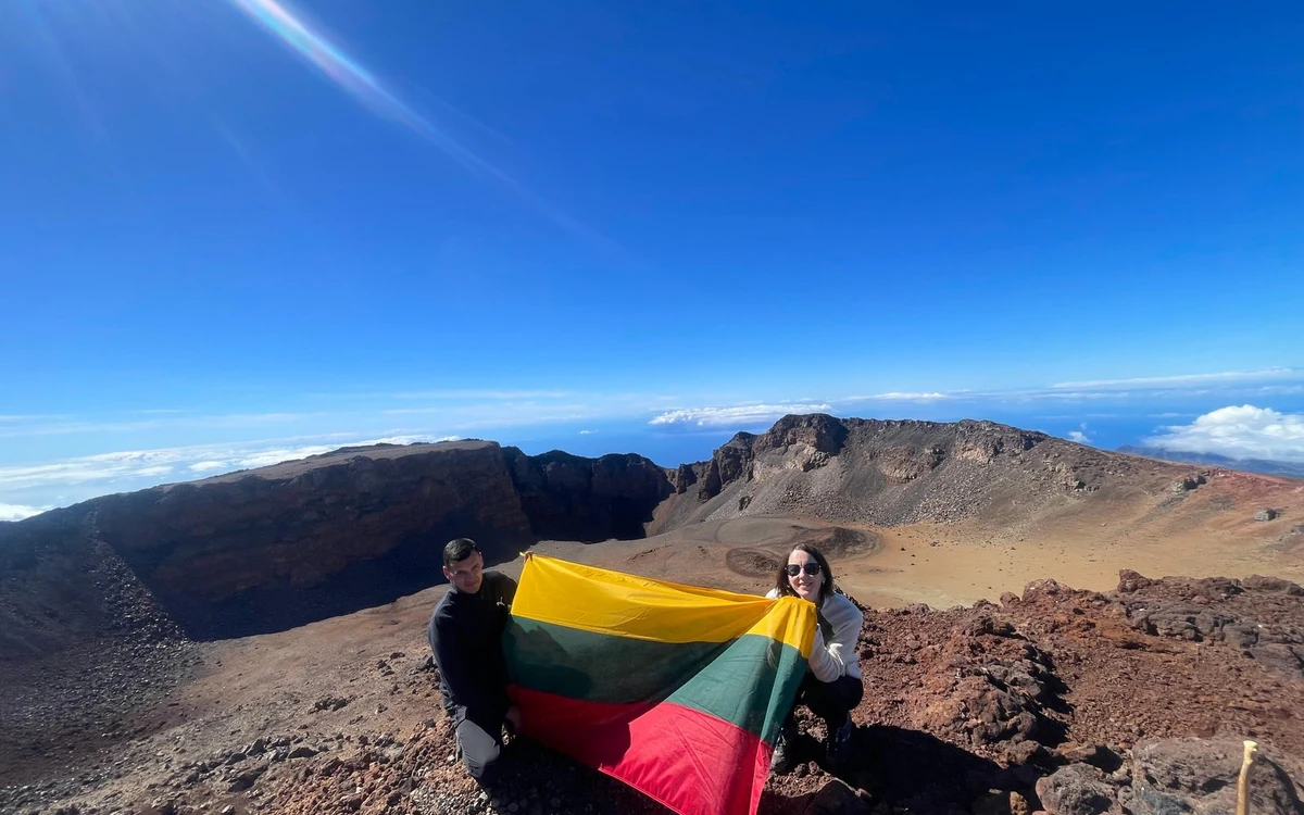 Eine Wanderin mit Flagge am Rand des Pico Viejo Kraters